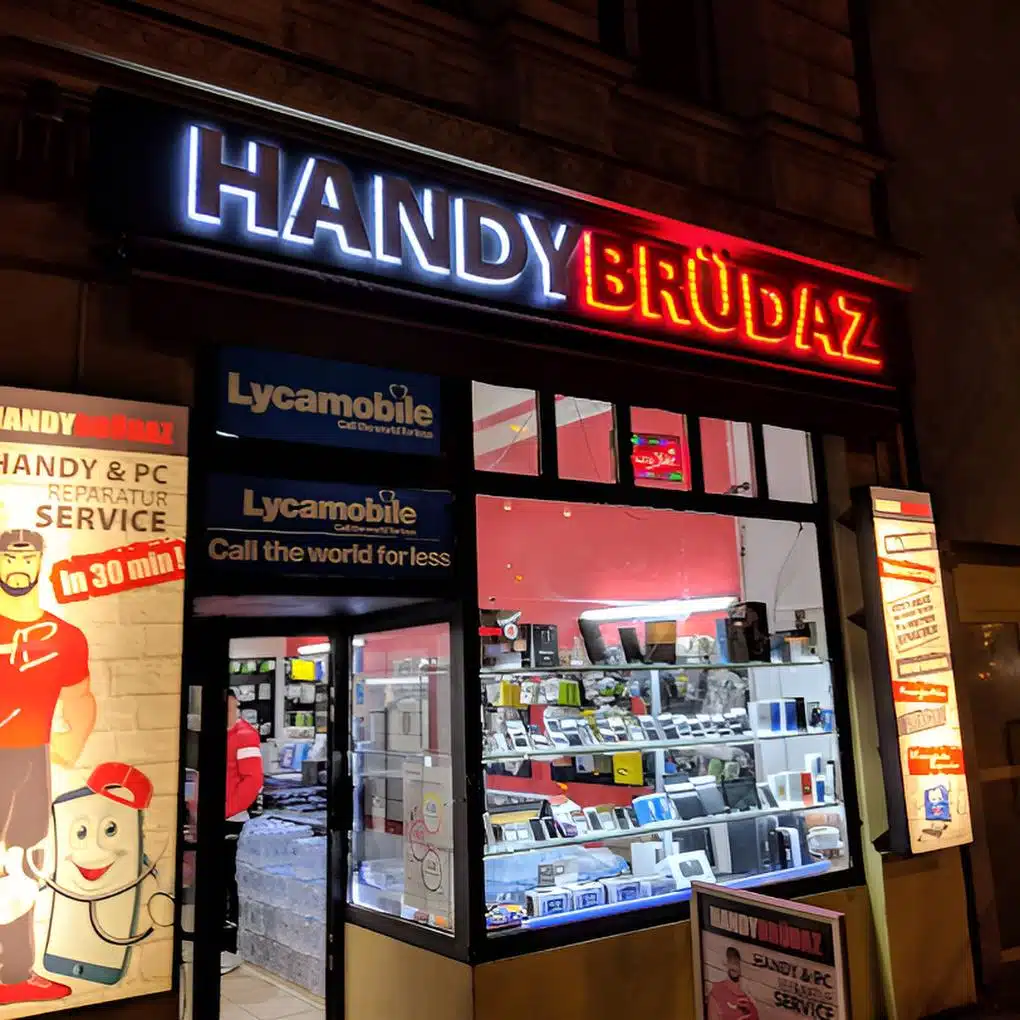 Beleuchtetes Ladengeschäft von HANDYBRÜDAZ bei Nacht in der Potsdamer Straße